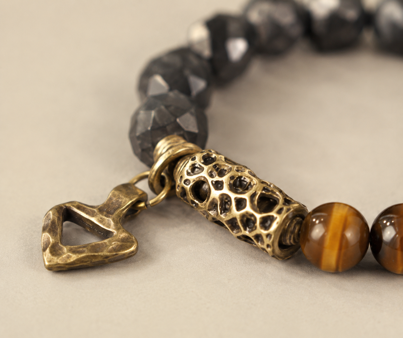 Hand-finished bronze barrel bead and hammered charm — detail view