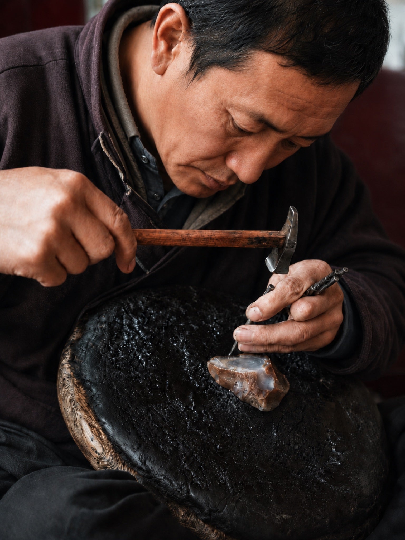 Tenzin, stone polisher in Lhasa, working an agate bead with hammer and point