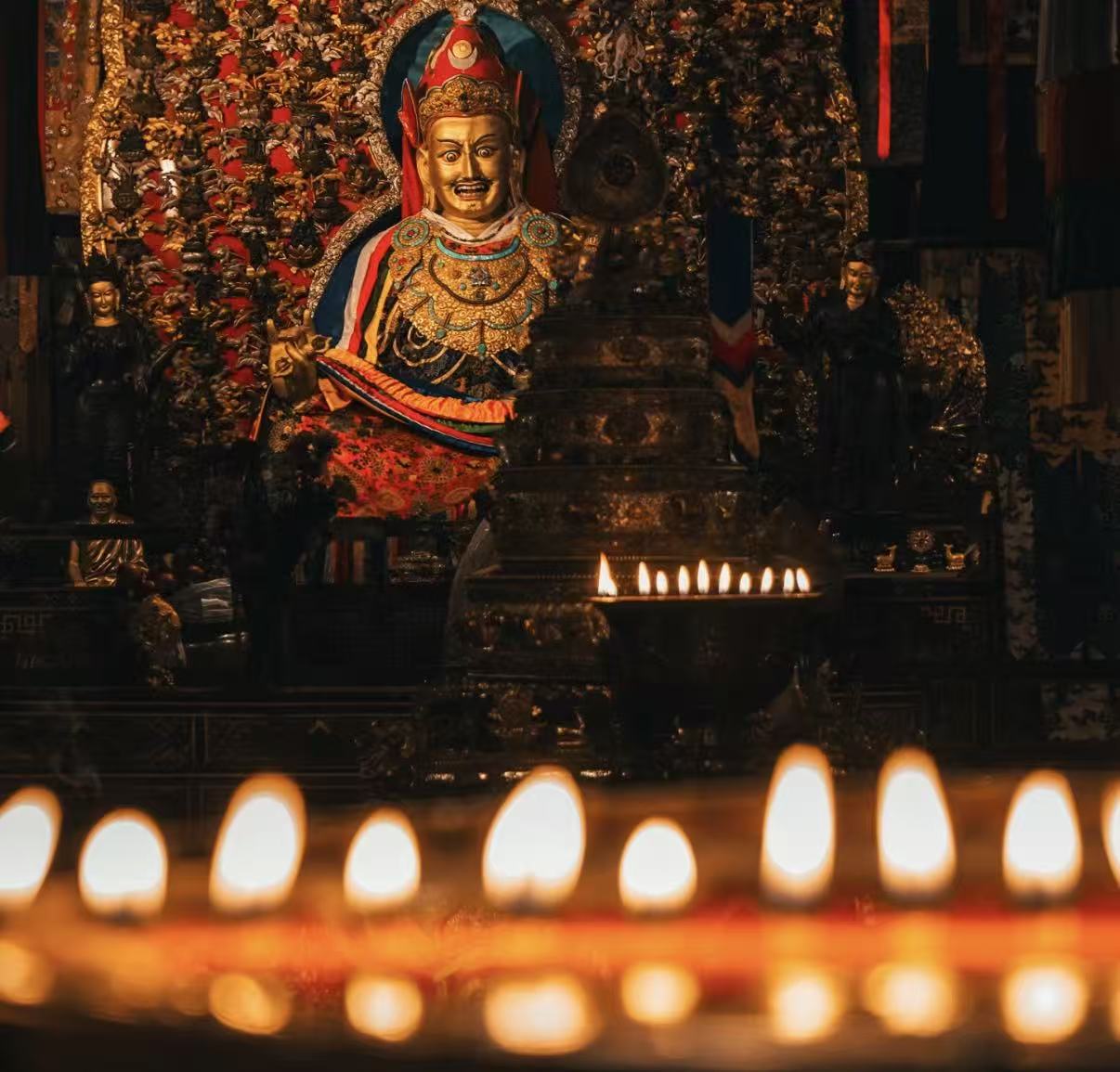 Butter lamps burning before a gilded deity in a Tibetan temple